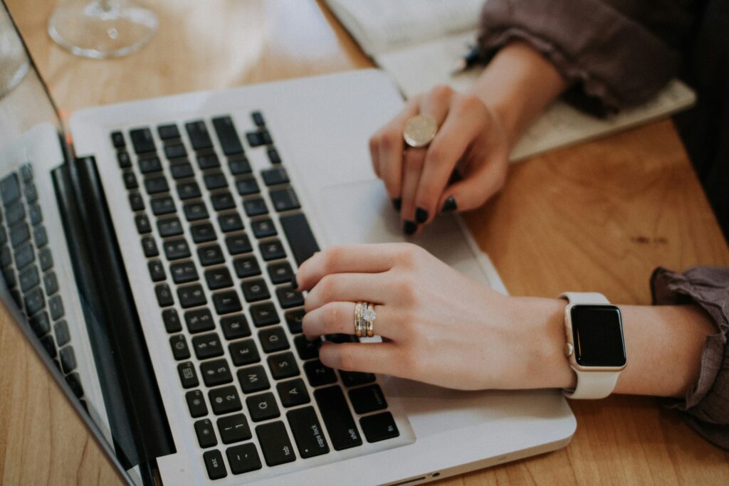 Person with a watch typing on lap-top
