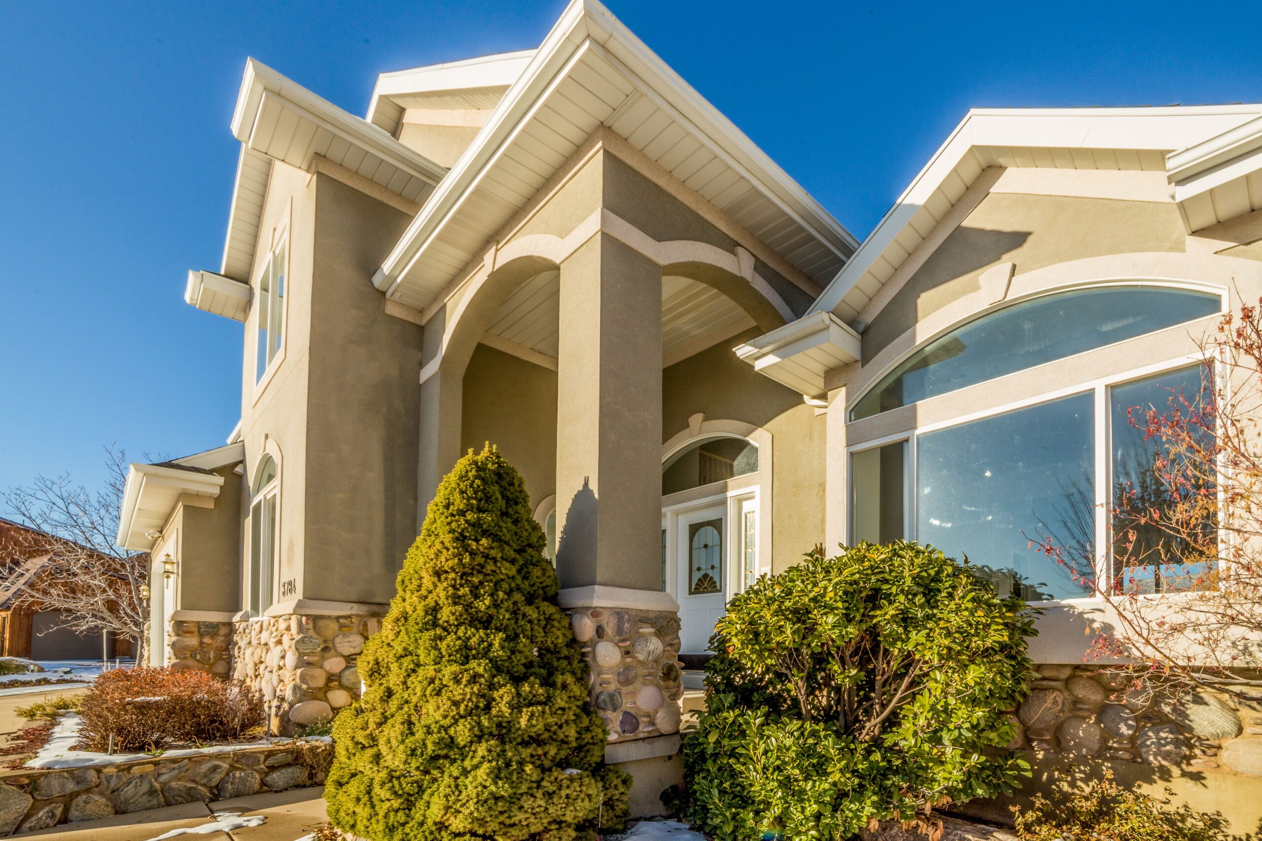 stucco house with front bushes